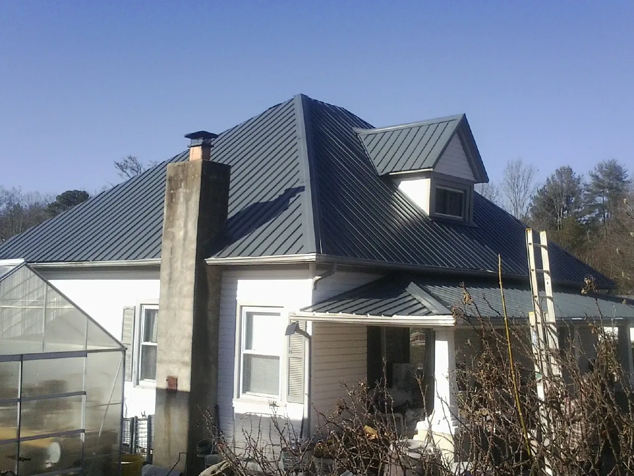 Dark blue standing seam metal roof on a white farmhouse with dormer — Slate & Tile Roof Repair by Roofing Brothers in Lincoln City